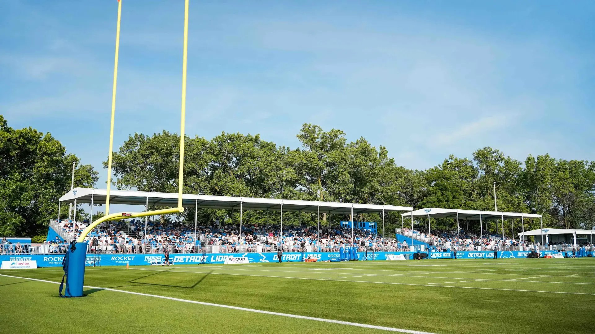InProduction shaded single-level hospitality deck with tiered seating and prominent sponsor branding installed on the field for Detroit’s summer training camp, providing improved comfort and clear sightlines for fans.