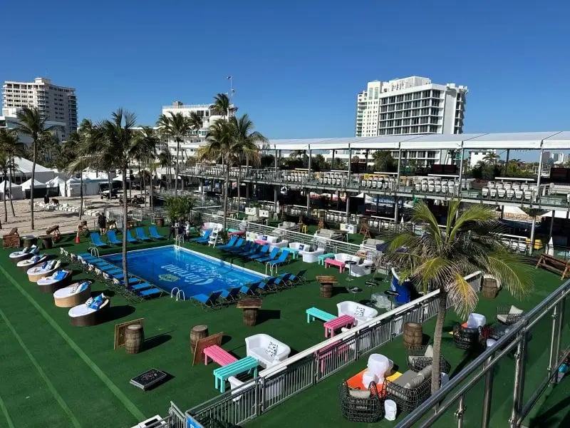 InProduction two-story beachside hospitality structure with bar seating, built-in pool, and elevated views overlooking the main stage at the Tortuga Music Festival.