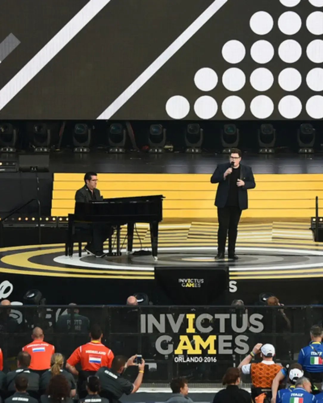 Custom circular stage designed and branded for an event, shown with a speaker presenting. 