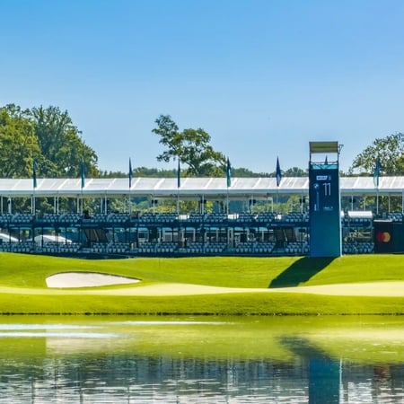 Temporary golf hospitality structure seen across a pond at an event site.