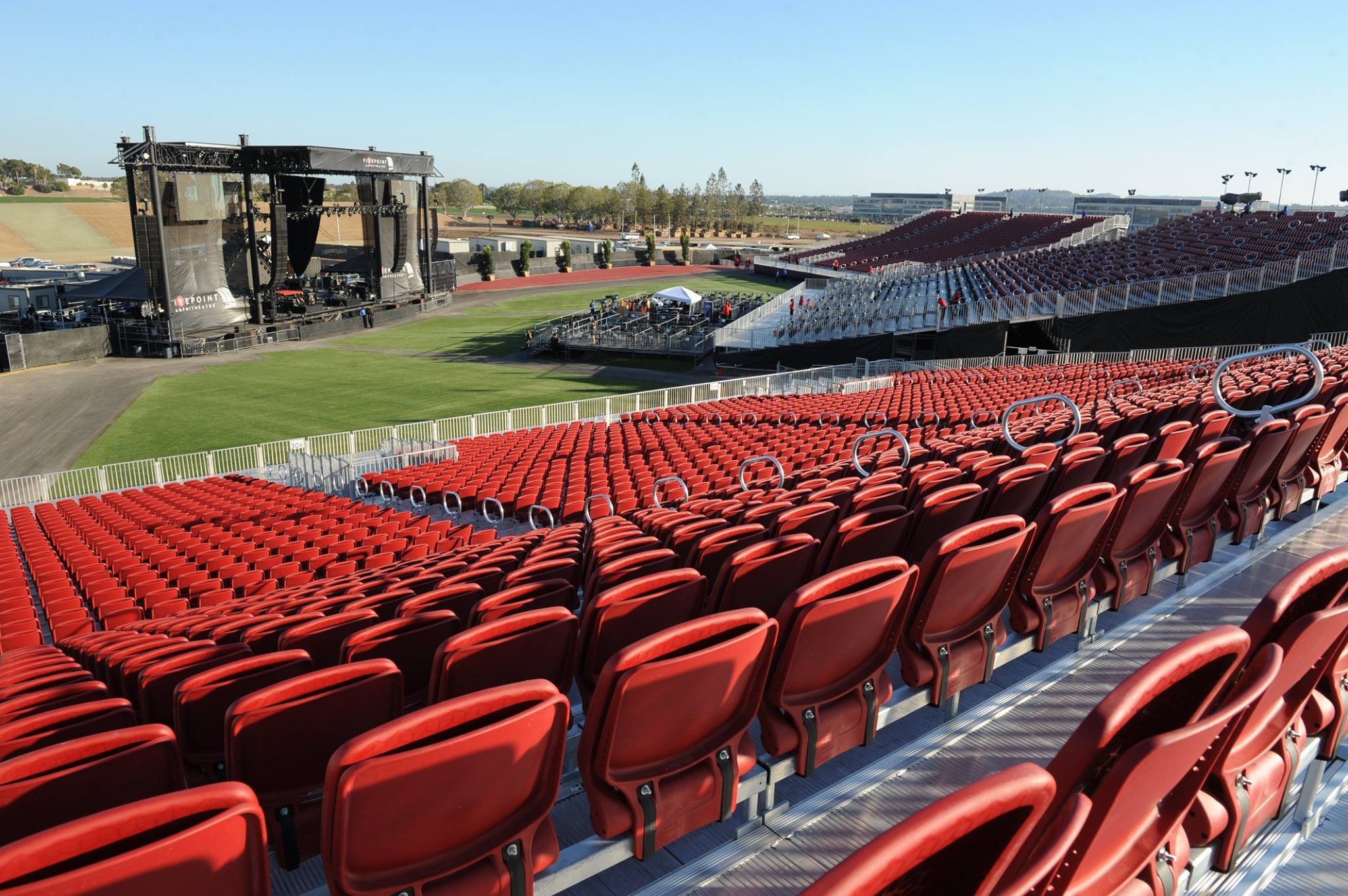 InProduction tiered amphitheater seating with red premium chairs oriented toward the stage, engineered for durability, comfort, and clear visibility.
